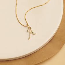 Gold-plated initial necklace showing different letter pendants for personalization.